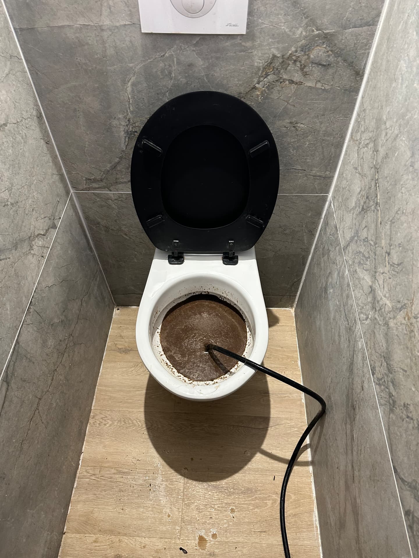 WC moderne bouché débouché au furet dans des toilettes carrelées — Évry-Courcouronnes
